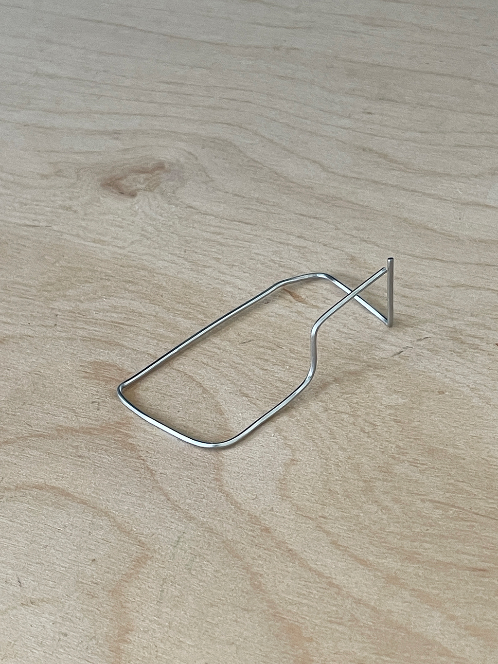 photograph of a bent paperclip resembling a boundary and a small gate