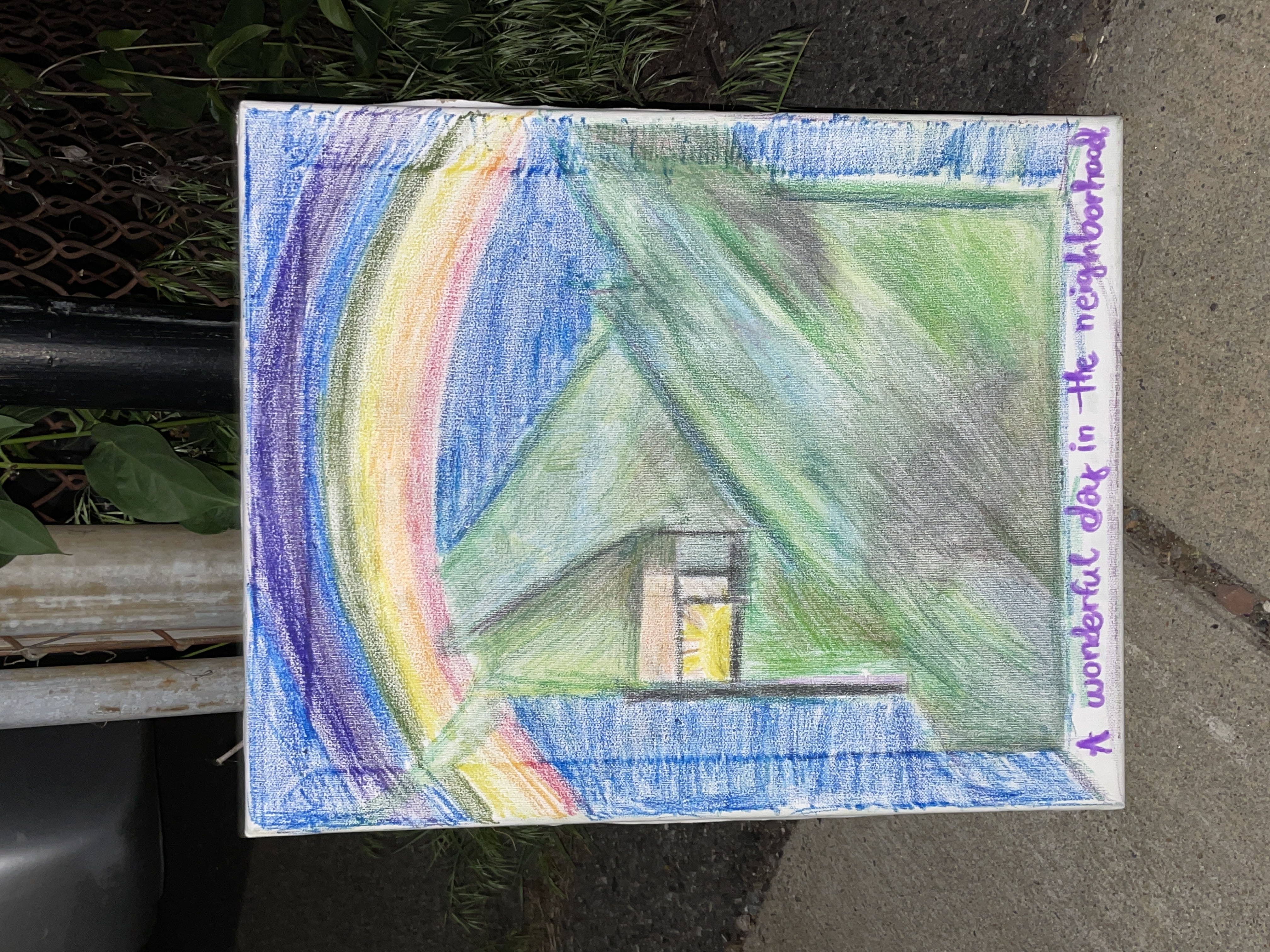 a drawing leaning against a fence-pole, reading: "A wonderful day in the neighborhood"