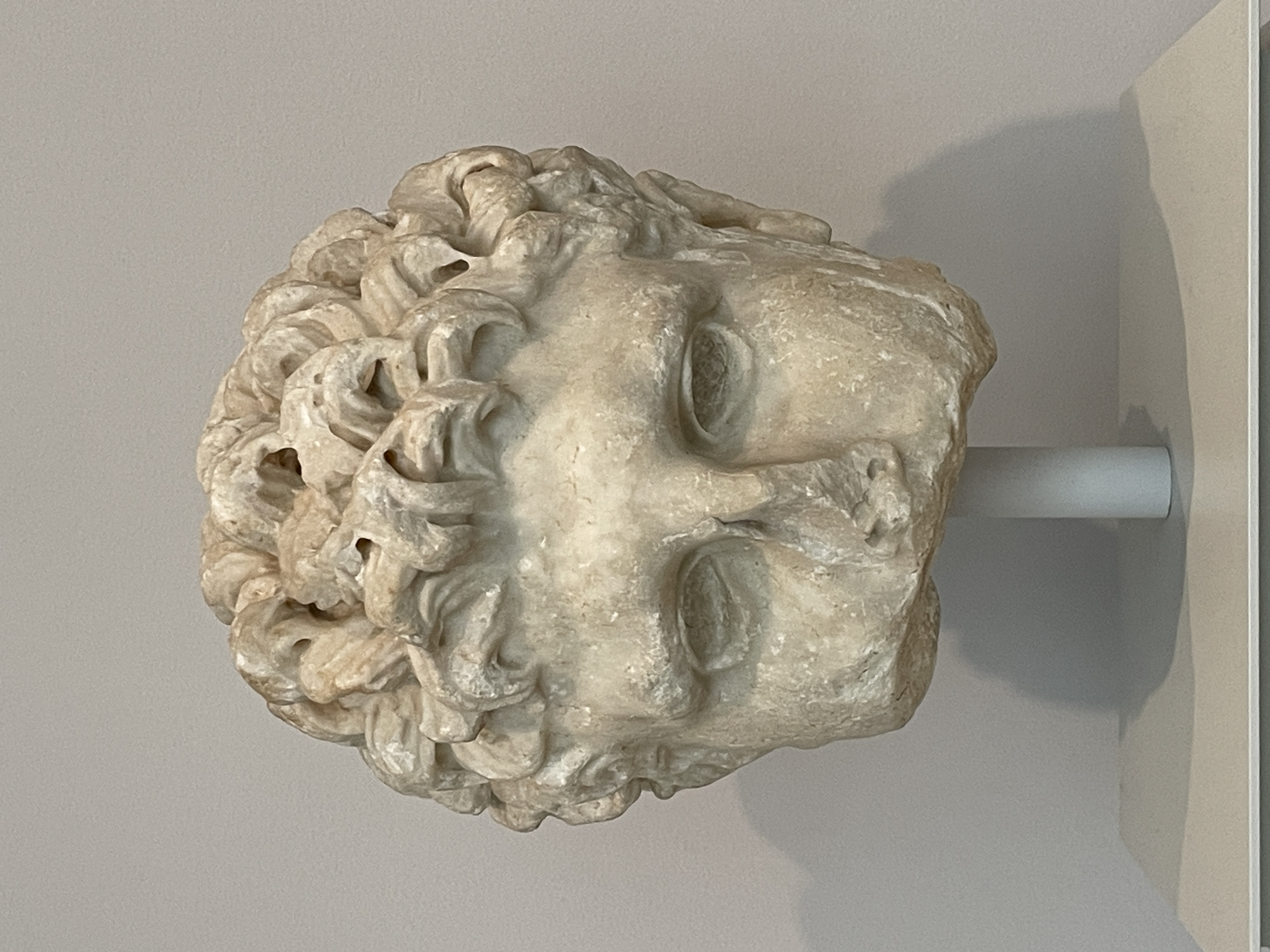 a sculpture of a man's head in marble, his chin broken off and his eyes hollow