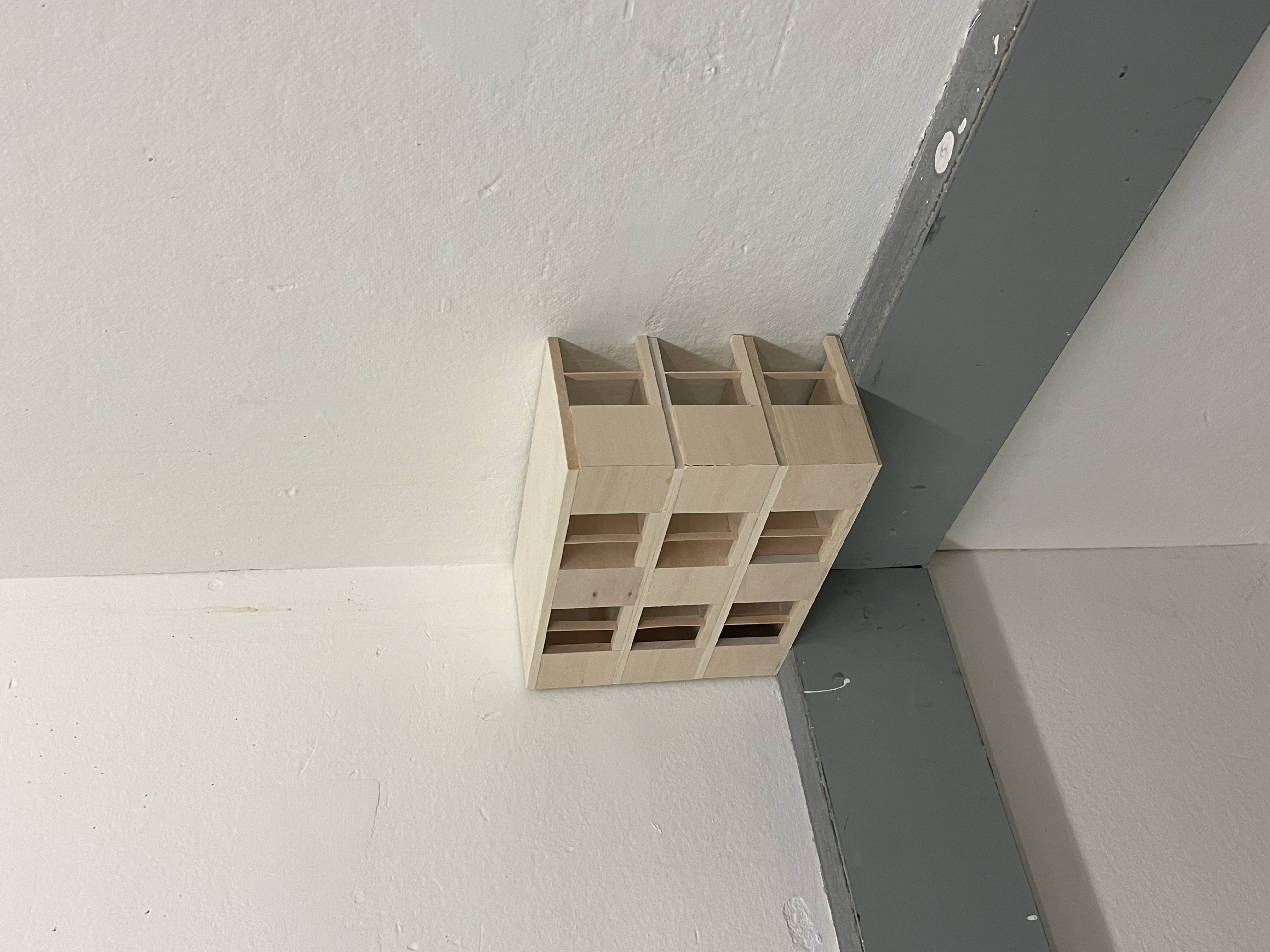 a wooden architectural model is pressed against the corner of two walls