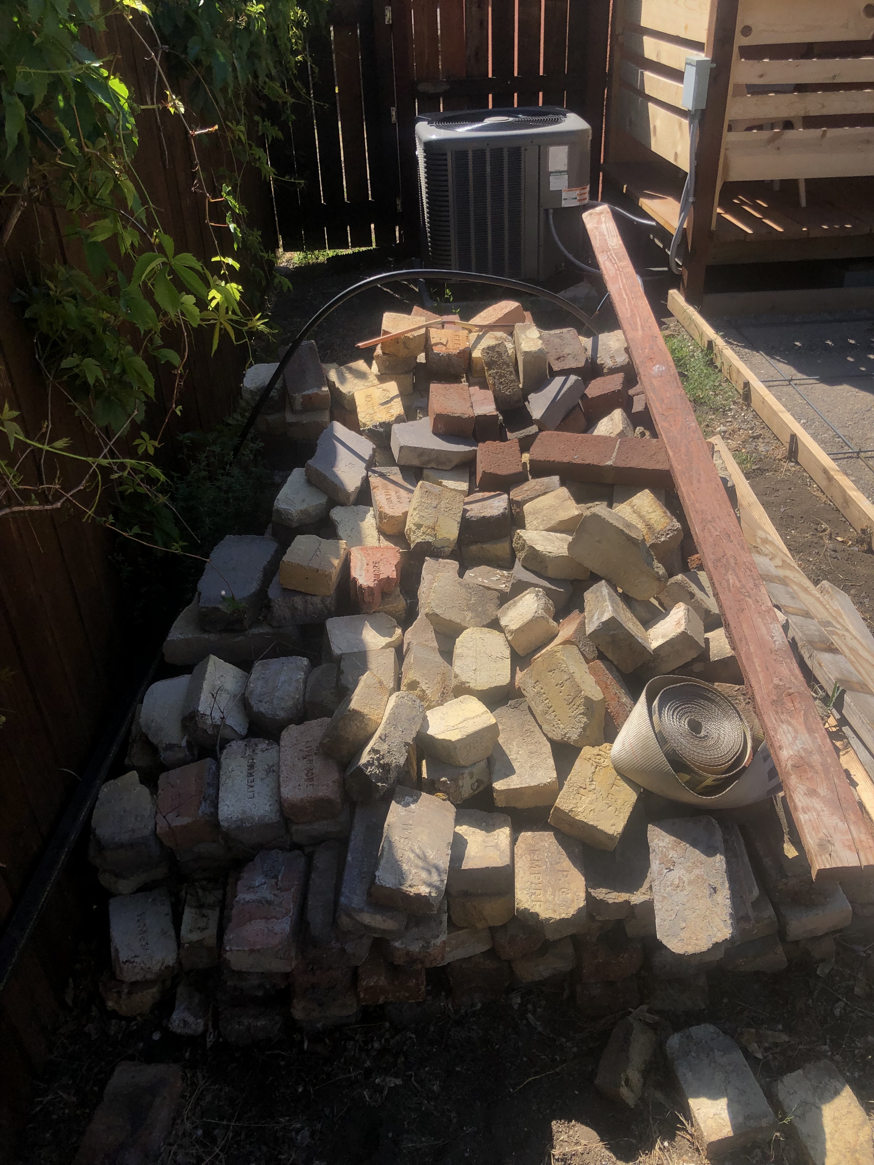 pile of bricks in a half-sunlit backyard