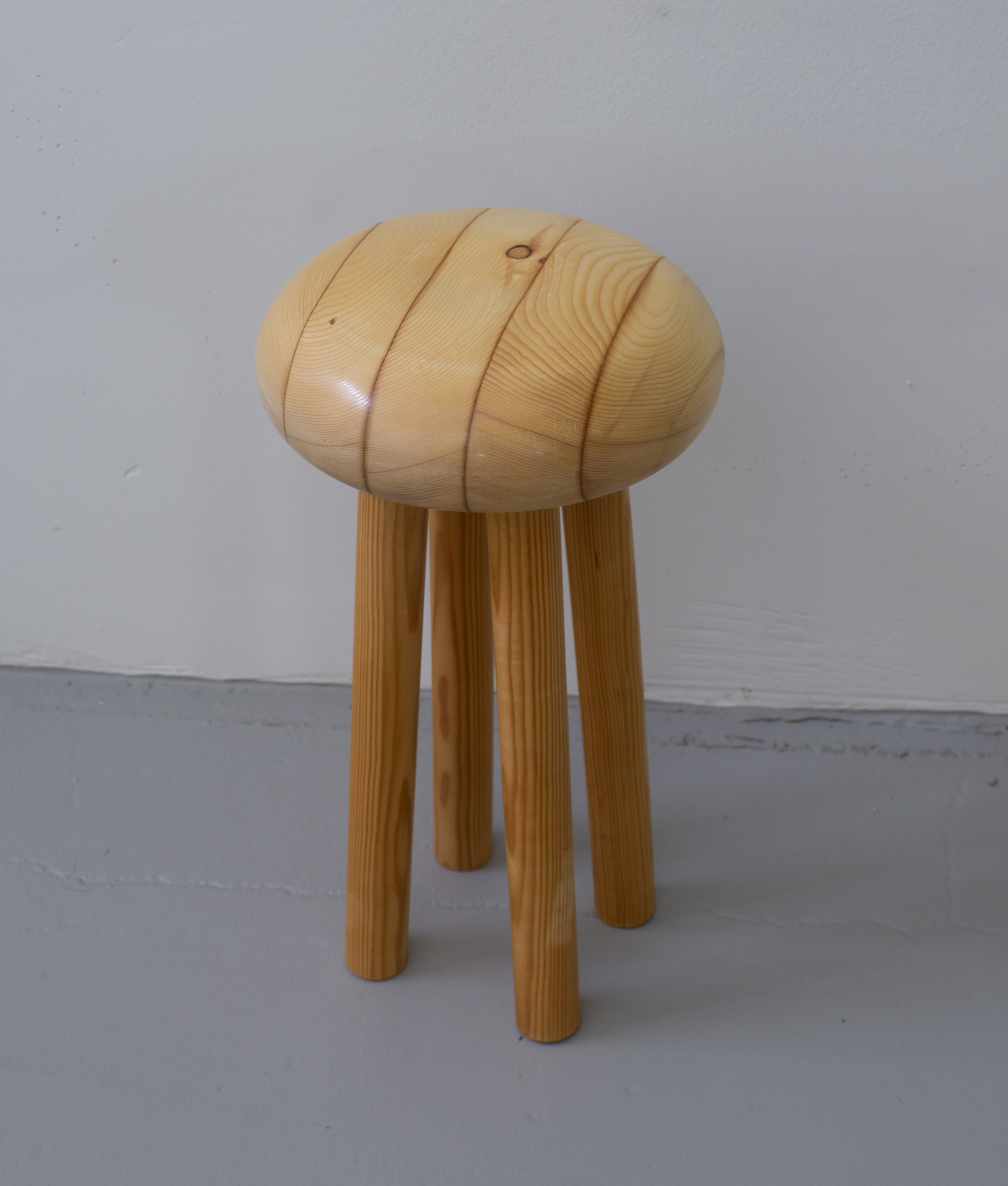 small wooden stool with four chunky, cylindrical legs
