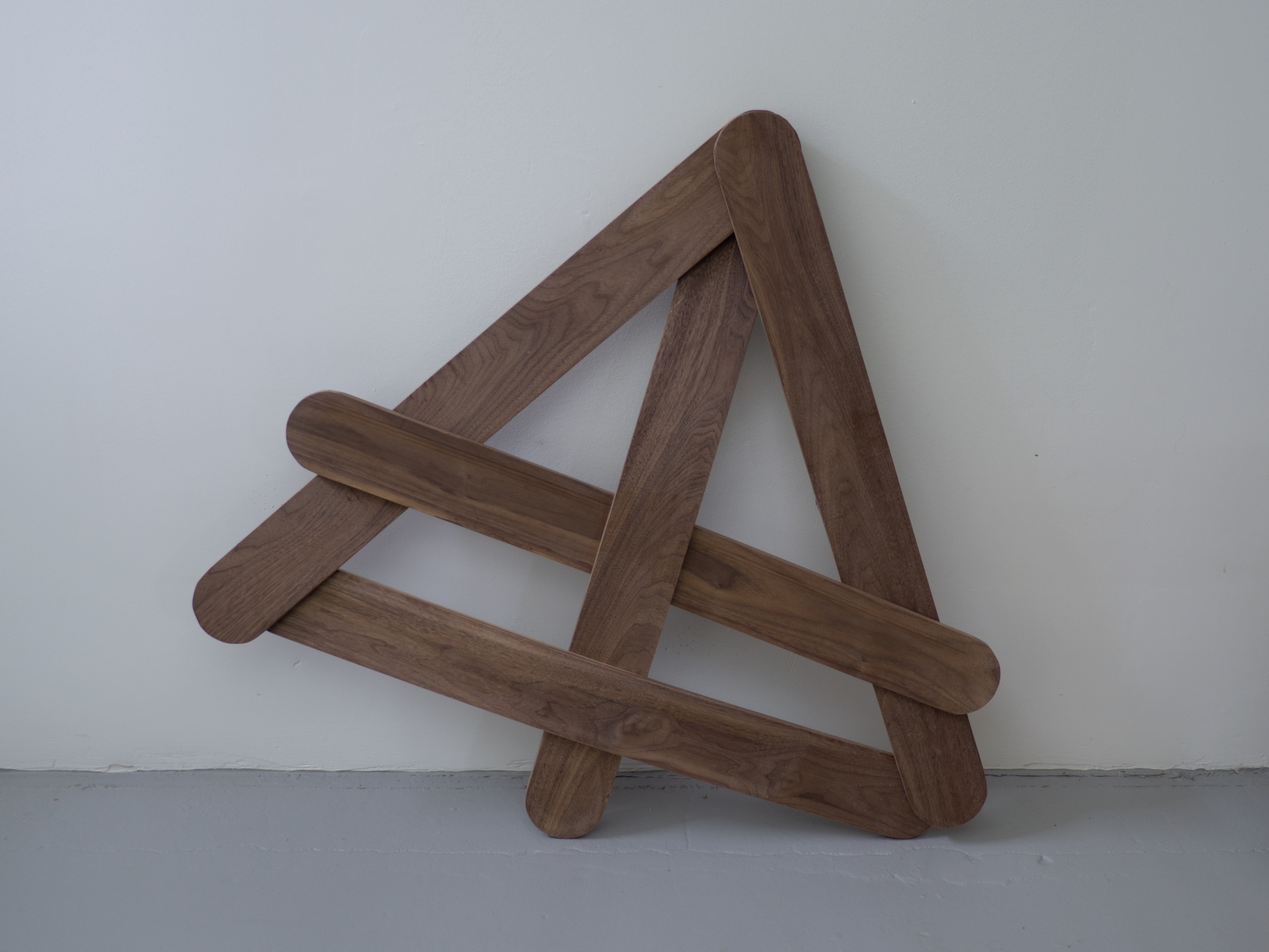a group of wooden members are held in tension on and over each other making up a triangular shape