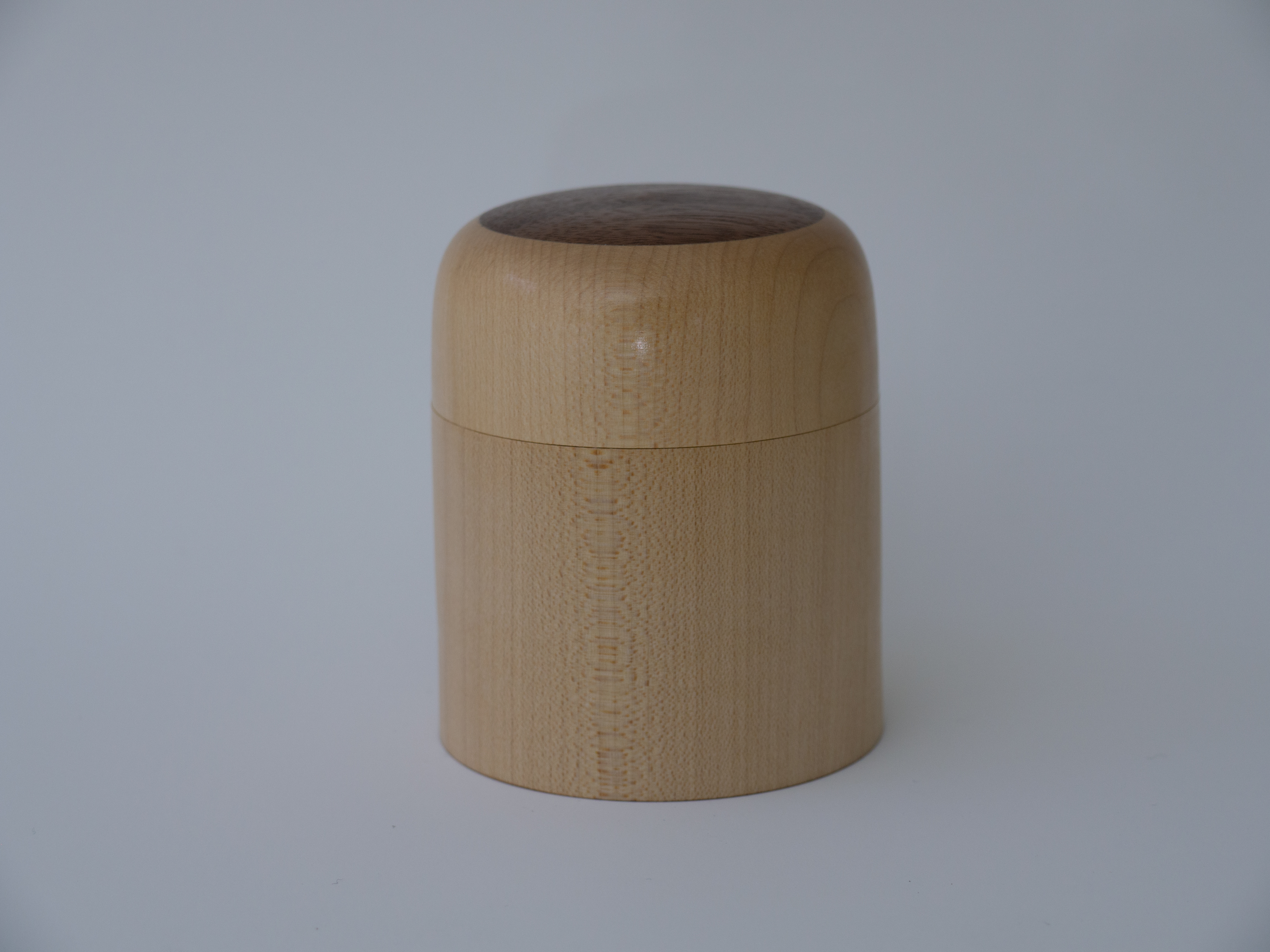 a small lidded box of wood with a walnut inlay on the lid sitting on a white background